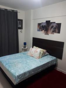 um quarto com uma cama com um edredão azul e cartazes em Apto Enseada Coral Gables no Guarujá