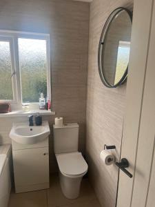 uma casa de banho com um WC, um lavatório e um espelho. em The cosy beach House em Llanelli