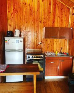 cocina con armarios de madera y nevera blanca en Cabañas Armonía del Ranco, en Lago Ranco