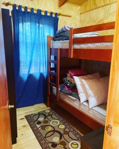 Habitación con 2 literas y cortinas azules. en Cabañas Armonía del Ranco, en Lago Ranco