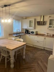 a kitchen with white cabinets and a wooden table at The cosy beach House in Llanelli