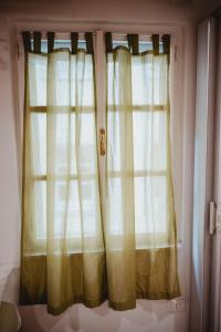 una ventana con cortinas blancas en un dormitorio en Monolocale Marino in centro storico, en Trieste