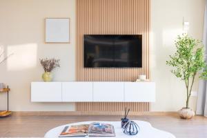 a living room with a television on a white cabinet at Paradise Holiday Home with Private Beach Access 605B2 in Abu Dhabi