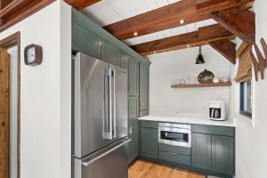 a kitchen with green cabinets and a stainless steel refrigerator at A-Frame on Balsam in Valle Crucis +24 photos