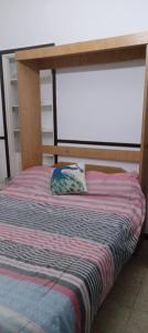 a bed with a wooden frame with a striped blanket at 8B Ambiente y medio con Balcon in Mar del Plata