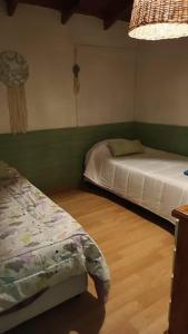 a bedroom with two beds and a wooden floor at Mi casa, tu casa. Entre Plottier y Neuquen. in Neuquén