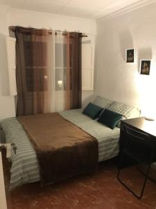 habitación en Alicante, Benalua في أليكانتي: غرفة نوم مع سرير مع وسائد خضراء ومكتب