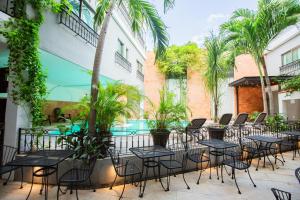 a patio with tables and chairs and a swimming pool at Hotel Nacional Merida in Mérida