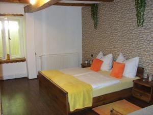 a bedroom with a bed with orange and yellow pillows at Apartment Bodza in Tompa