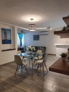 a dining room and living room with a glass table and chairs at Departamento Tucán in Cancún