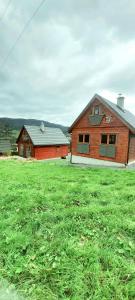 Eine Scheune und ein Haus auf einem Grasfeld in der Unterkunft Nad Cicha in Ujsoły