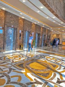 فندق ملاك الصفوة في مكة المكرمة: رجل يمشي في لوبي بطابق فسيفسائي