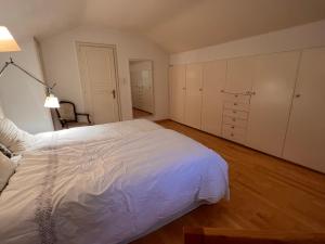 a bedroom with a large white bed and wooden floors at Le Cottage in Vésenaz