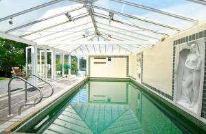 an indoor swimming pool with a glass roof at Water Edge in Dittisham