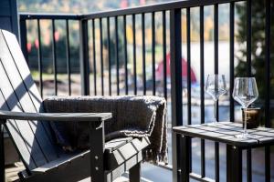a chair and a table with wine glasses on a balcony at Ski & Tee Retreat Bright Three Bedroom and Hot Tub in Revelstoke