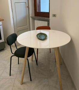 una mesa blanca con dos sillas y un plato en ella en NICE - camere con bagno privato, en Lioni