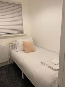 a white bed with a pillow on it in a room at Modern 3 Bed House in Dagenham