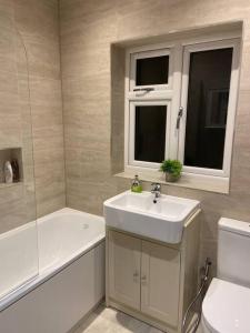a bathroom with a sink and a tub and a toilet at Modern 3 Bed House in Dagenham