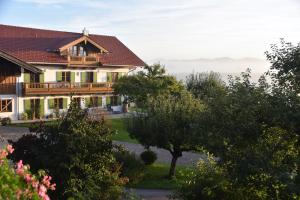 ein großes Haus mit einem Balkon und einem Baum in der Unterkunft Ferienwohnung beim Hainz in Dietramszell