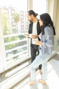 a man and a woman standing in front of a window at Downtown Oasis - Spacious Modern 3-BR Flat near Beachpark in Antalya