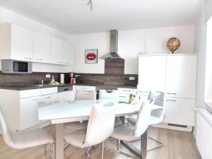 a kitchen with white cabinets and a white table and chairs at Paris Winterberg Ferienwohnung 6 Pers WiFi in City near Lift in Winterberg