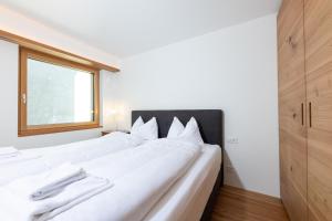 a large white bed in a room with a window at New! Exclusive Apartment 3min to Chantarella Bahn in St. Moritz