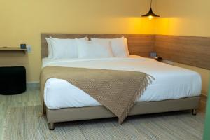 sypialnia z dużym łóżkiem z białą pościelą i poduszkami w obiekcie NOVO Hotel Boutique w mieście Ríohacha