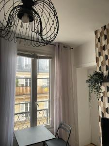 Habitación con mesa, ventana y lámpara de araña. en Bastille Cosy Flat Paris, en París