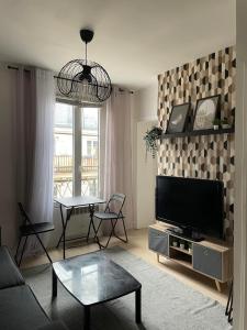 sala de estar con TV de pantalla plana y mesa en Bastille Cosy Flat Paris, en París