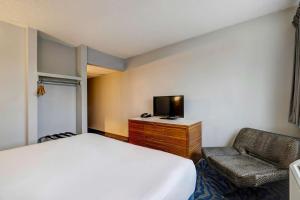 Schlafzimmer mit einem Bett, einem TV und einem Stuhl in der Unterkunft Motel 6 Arlington TX Entertainment District in Arlington
