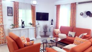 een woonkamer met oranje meubels en een televisie bij Villa 3 Chambres Salon Adidogomé in Fazao