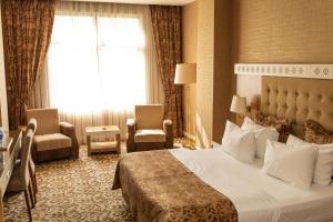 une chambre d'hôtel avec un lit, des chaises et une fenêtre dans l'établissement Graaf Hotel, à Baku