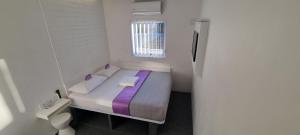 uma pequena cama num pequeno quarto com uma janela em Check Inn Hotel em Cidade do Cabo