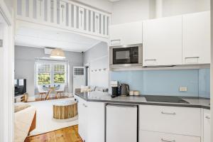 een keuken met witte kasten en een woonkamer bij THE OSLO on Broadway with Pool Villas 1 & 2 in Glenelg