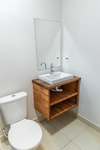 La salle de bains est pourvue de toilettes blanches et d'un lavabo. dans l'établissement Praia Camburi - Studios Kuta, à Camburi