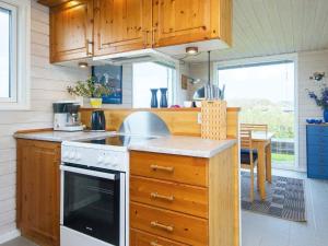 レムヴィーにある5 person holiday home in Lemvig-By Traumの木製のキャビネットとコンロ付きオーブンを備えたキッチン +18枚の写真