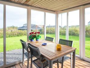 a wooden table and chairs on a porch with windows at Three-Bedroom Holiday home in Lemvig 1 in Lemvig