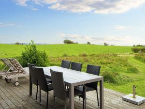 a table and chairs on a deck with a view of a field at 8 person holiday home in Knebel in Knebel