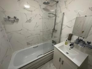 a white bathroom with a tub and a sink and a mirror at Studio Room In Brighton in Brighton & Hove +1 photo