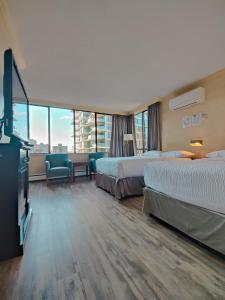 a hotel room with two beds and a flat screen tv at Divya Sutra Suites on Robson Downtown Vancouver in Vancouver