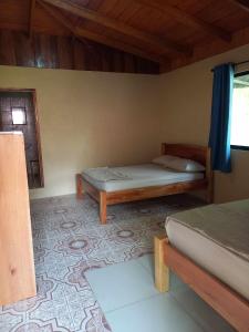1 dormitorio con 2 camas, ventana y alfombra en Surf Shack Room #3 en Pavones
