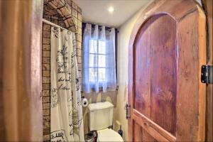 a bathroom with a toilet and a wooden door at Hacienda - Private Guest Studio in Los Gatos