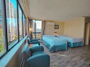 a hotel room with two beds and chairs and windows at Divya Sutra Suites on Robson Downtown Vancouver in Vancouver