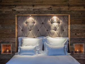 1 dormitorio con 1 cama grande con sábanas y almohadas blancas en Kitz Boutique Chalet am Lift, en Kirchberg in Tirol