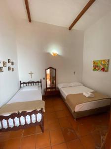 een slaapkamer met 2 bedden en een kruis aan de muur bij Mi casita “Chinco” estrellas in Zapatoca