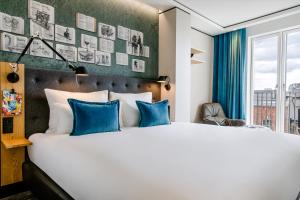 ダブリンにあるMotel One Dublinのベッドルーム(青い枕の大きな白いベッド付)