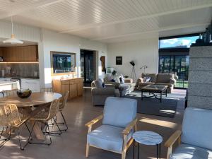 Cooks Beach的住宿－The Admiral，厨房以及带桌椅的起居室。