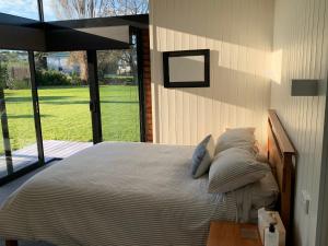 una camera da letto con un grande letto con una grande finestra di The Admiral a Cooks Beach
