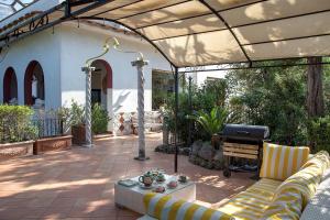 a covered patio with a couch and a grill at Villa Gianturco - Luxury In The Green Island in Ischia