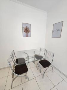 桑托斯的住宿－ÓTIMO APARTAMENTO - UMA QUADRA DA PRAIA EM SANTOS，房间里的三把椅子和一张玻璃桌